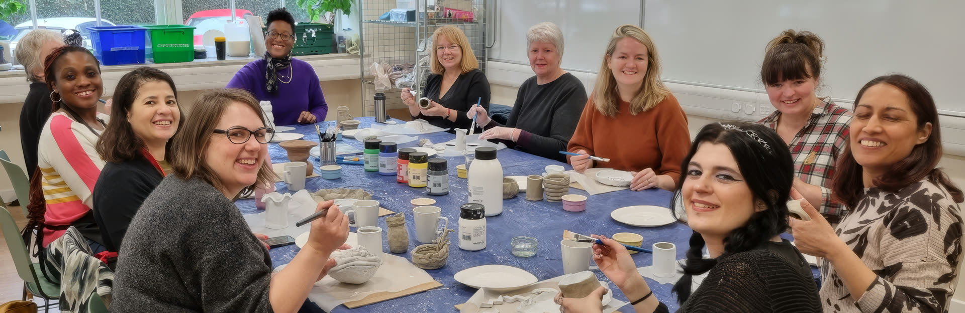 Clay workshop at Duncan Place — a table of smiling participants painting pottery